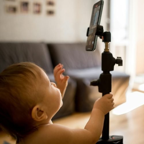 a little boy reaches for the phone on a tripod. Kids and Gadgets